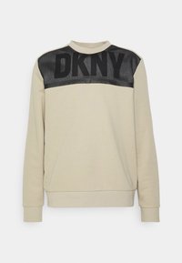 Felpa beige con pannello superiore in rete nera e logo "DKNY" in grassetto. Presenta polsini a costine e design a girocollo.