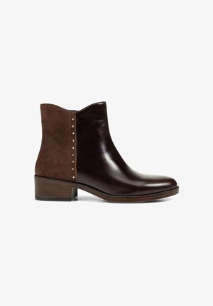 Bottine marron avec un devant en cuir lisse, à l'arrière en daim, petit talon et clous dorés le long de la couture latérale, photographiée sur un fond blanc.