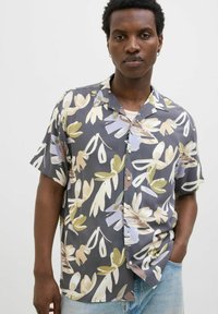 Chemise à manches courtes, boutonnée, de couleur gris foncé avec un motif floral. Comprend des tons pastel de vert, bleu et marron ; tissu lisse et léger.