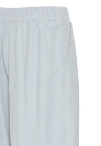 Šviesiai mėlyni, lengvi kelnių su elastine juosta ir šoninėmis kišenėmis. Audinys turi lygų tekstūrą ir šiek tiek laisvą siluetą.