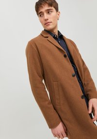 Cappotto in misto lana marrone con una vestibilità sartoriale, design monopetto, rever a punta e tasca laterale. Tessuto testurizzato e bottoni neri.
