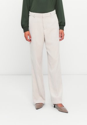 Beige corduroy trousers with a straight leg, featuring a flat front and belt loops. Paired with a dark green blouse and high heels.