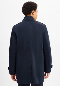 Marineblauwe trenchcoat met een gladde textuur, knielange ontwerp, schouderepauletten en een achterkantventilatie voor gemakkelijke beweging.