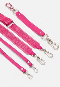 La laisse de chien multifonctionnelle rose présente des largeurs de sangle variées, un matériau en nylon, des accessoires en métal argenté et des détails avec logo. Design durable et ajustable.