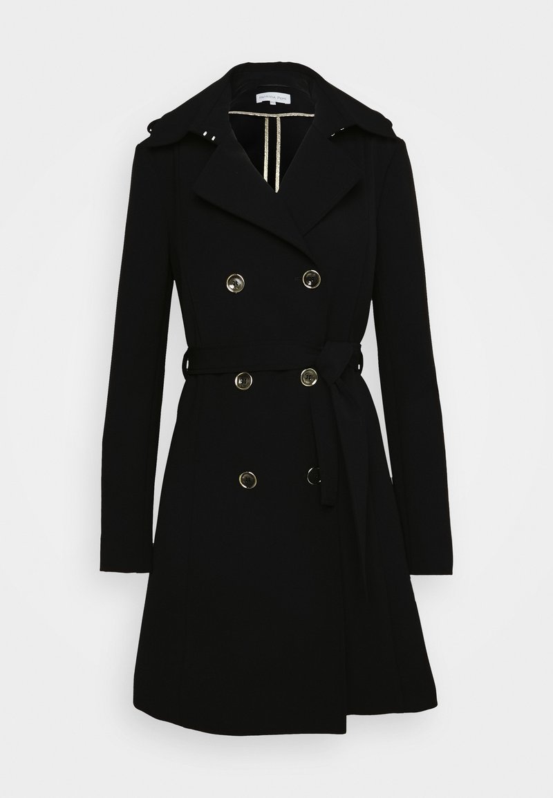 Trench-coat noir croisé à boutons dorés, larges revers, taille ceinturée et manches longues sur fond blanc.