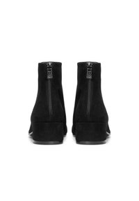 Botines de ante negros con un bajo tacón cuadrado, que presentan una cremallera central en la parte posterior y una textura suave.