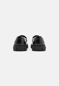 Schwarze Leder Schuhe mit glatter Oberfläche, dicke Gummisohle und rundem Design. Verfügt über eine offene Ferse und einen gepolsterten Kragen für Komfort.