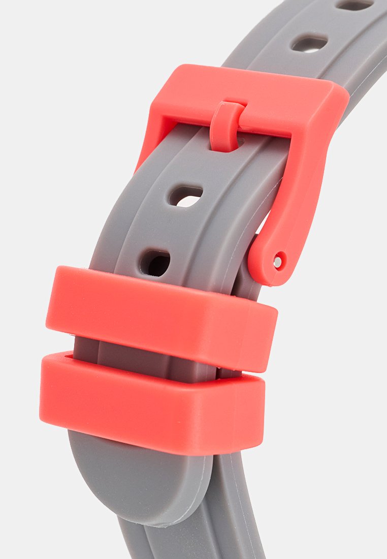 Correa de reloj de silicona en gris con una hebilla y acentos en coral brillante. Presenta agujeros para ajustarse y una textura suave y flexible.