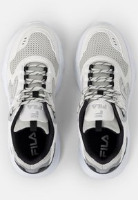 Hvite atletiske sneakers med mesh-paneler, teksturerte detaljer, svart og grå dekor, runde lisser og synlig merkevare på tungen.
