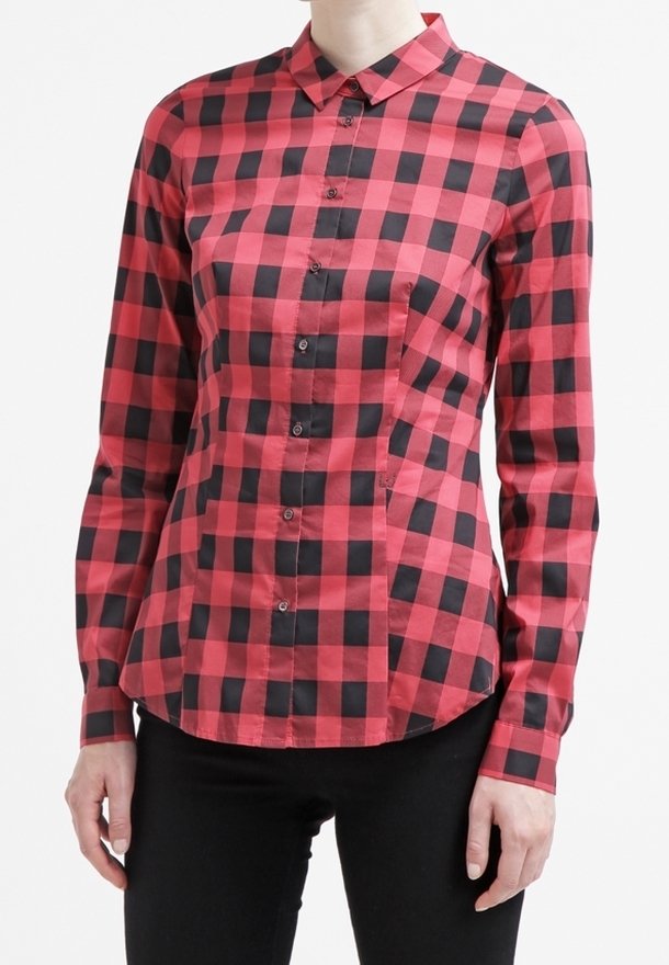 Camicia a quadri rossi e neri, con maniche lunghe, colletto e una forma aderente, caratterizzata da bottoni visibili e una tasca laterale.