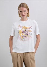 White cotton t-shirt with a graphic print featuring a tiger and celestial elements in pink and yellow hues. Short sleeves and relaxed fit.
