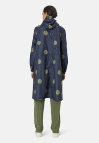 Navy polkaprikket regnfrakke med store olivengrønne prikker. Har hætte, elastiske manchetter og et afslappet design i knælængde.