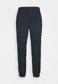 Mustat urheiluhousut, jotka on valmistettu kevyestä kankaasta. Niissä on joustava vyötärönauha nyörillä, kapenevat lahkeet ja sivutaskut.