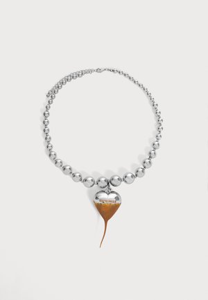 Collier de perles en argent avec un pendentif en forme de cœur partiellement couvert de rouille et le mot "OTTOLINGER" gravé en haut.