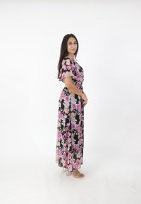 Robe maxi en tissu noir transparent avec un motif floral rose et pêche, dotée d'un décolleté en V et de manches flottantes, taille cintrée et jupe fluide.