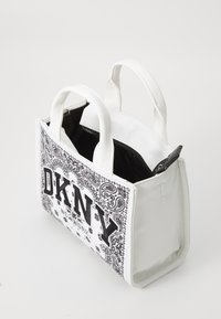 Balta rankinė su juodu paisley raštu ir ryškiu "DKNY" logotipu. Mažos rankenos, užtrauktukas ir išklotas vidus. Stačiakampio formos.