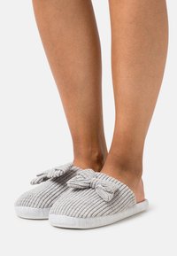 Gray, ribbed slippers with a soft texture, featuring a bow accent on the front and a cushioned white sole. Open-back design.