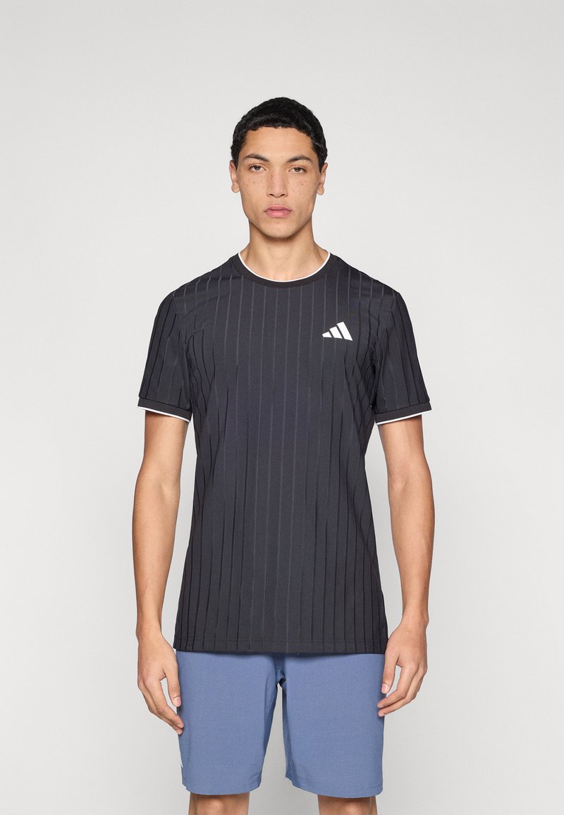 Maglietta sportiva nera con righe verticali, maniche corte e scollo rotondo bianco. Presenta un logo Adidas bianco sul petto a sinistra.