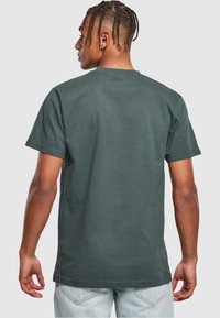 Mørkegrøn bomulds-t-shirt med korte ærmer, rund hals og en afslappet pasform. Bagsiden er simpel uden synlige mønstre eller detaljer.