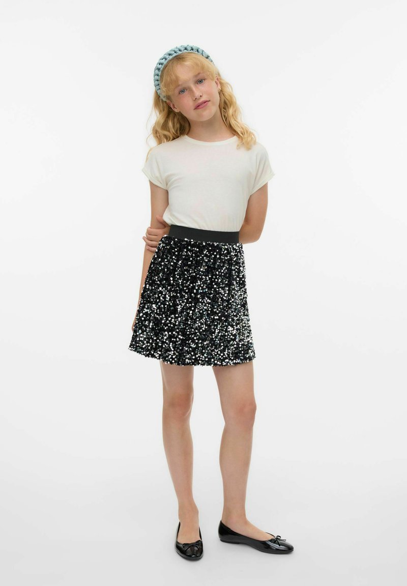 Camicia bianca a maniche corte, gonna nera con paillettes e scarpe basse nere. Presenta un design testurizzato e lucido, con una comoda vita elastica.