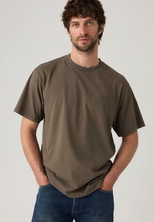 Olijfgroene katoenen t-shirt met een ronde hals, korte mouwen en een subtiele logo-detail, gecombineerd met blauwe spijkerbroek.