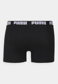 Black boxer shorts made of smooth fabric featuring a wide elastic waistband with white "PUMA" branding. Fitted design with a mid-thigh length.