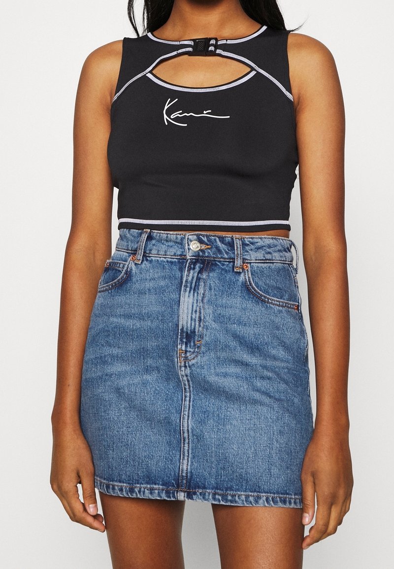 Svart kortärmad crop-top med ett nyckelhål och grå detaljer, kombinerad med en högmidjad blå denimkjol med en framseam och fickor.