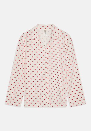 Fehér gombos ing hosszú ujjakkal, amelyen apró piros szívek mintázata látható. Könnyű, texturált anyagból készült.