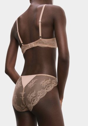 Sujetador de encaje nude y braguitas a juego, con patrones de encaje floral, tirantes ajustables y un acabado suave. Tejido suave y semi-translúcido.