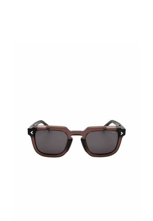 Occhiali da sole quadrati marroni e neri con lenti scure e sottili dettagli bianchi a forma di freccia agli angoli della montatura.