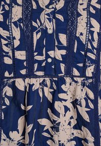 Robe bleu marine avec un motif floral en rose clair, comprenant des boutons, des accents en dentelle et une taille froncée. Tissu texturé avec des lignes verticales.