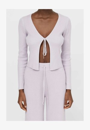 Fialkový žebrovaný pletený krátký kardigan s dlouhými rukávy, hlubokým výstřihem do V a zavazováním vpředu. Doplněn odpovídajícími kalhotami.