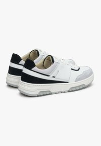 Witte en grijze sneaker met een zwarte suede accent, voorzien van een ronde neus, vetersluiting aan de voorkant en een dikke zool met profiel. Geweven materialen zijn zichtbaar.