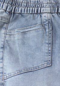 Light blue denim fabric with a gathered elastic waistband, featuring a back pocket and contrasting stitching along the edges.