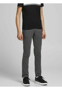 Graue Sweatpants mit Slim-Fit, ausgestattet mit seitlichen Reißverschlusstaschen und einem weichen, strukturierten Stoff, kombiniert mit schwarzen Sportschuhen.