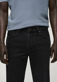 Jeans negri din denim cu o croială clasică, având buzunare frontale, o textură subtilă și închidere cu capse standard.