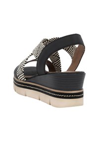 Black and white platform sandals with woven textile upper, featuring a thick sole and curved heel, exhibiting a layered design and stitching accents.