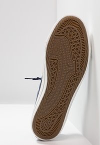 Dockers sneaker sole featuring a textured brown rubber outsole, white side strip, and navy upper with a round toe and laces.