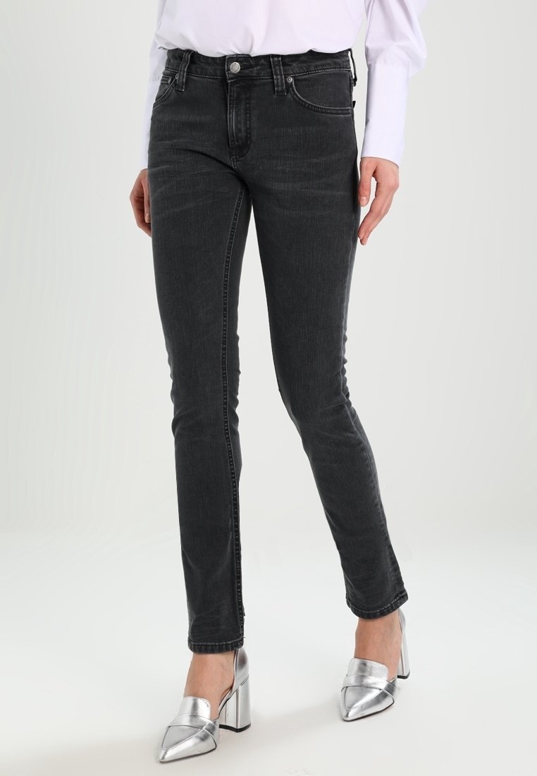 Svarta slim fit jeans med medelhög midja, med klassisk femficksdesign, dragkedja och subtilt blekt mönster. Kombineras med silverfärgade klackar.