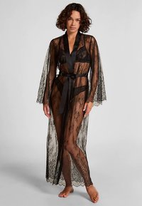 Zwarte kanten kimono met lange mouwen, doorzichtig stof, een satijnen ceintuur in de taille en bloemmotieven over het gehele kledingstuk.