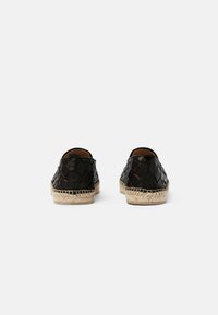 Scarpe in pelle intrecciata nera con design arrotondato, dotate di una suola in juta naturale e una texture liscia sul retro.