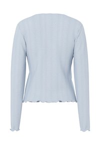 Γαλάζια πλεκτή μπλούζα μακριάς μανίκας με κάθετες υφασμάτινες ρίγες και κυματιστά τελειώματα στο τελείωμα και τις μανσέτες, εμφανίζεται από πίσω.