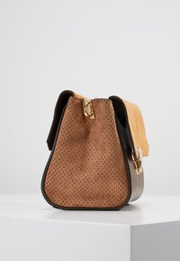 Brązowa torebka z zamszu z teksturowaną pomarańczową klapą, złotymi elementami i stukturalnym kształtem. Ma perforowane detale z tyłu.