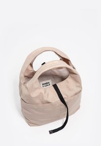 Beżowa torebka z miękkiego materiału z okrągłymi uchwytami, czarnym paskiem i widoczną metką "BIMBA Y LOLA" wewnątrz otwarcia torebki.