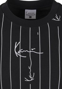 Schwarzes T-Shirt mit weißen vertikalen Streifen und abstrakter weißer Linienzeichnung eines Gesichts mit kursivem Text darüber, Größe Large gekennzeichnet.