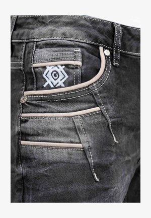 Zwarte denim jeans met een opvallend geborduurd ontwerp op de achterzak, met contrasterende beige stiksels en meerdere zakdetails.