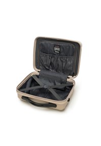 Valigia rigida beige con un interno foderato in nero, tasca con zip, cinghie elastiche e maniglia superiore per un facile trasporto.