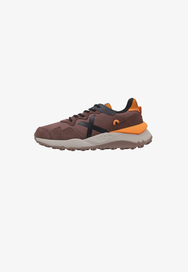 Chaussure de sport en suède marron et mesh avec des accents noirs, un talon orange et une semelle extérieure texturée. Elle dispose de lacets traditionnels et d'un col rembourré.