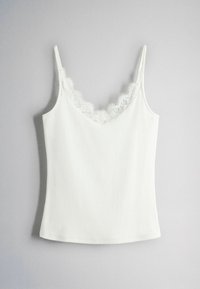 Weißes ärmelloses Camisole mit Spitzenbesatz entlang des V-Ausschnitts, aus geripptem Stoff, vor einem schlichten grauen Hintergrund gezeigt.