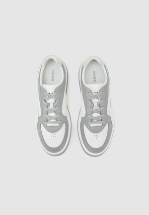 Grå og hvide atletiksneakers med en glat læderoverdel, polstret krave, rund tå og snørelukning. Diskrete perforeringsdetaljer.